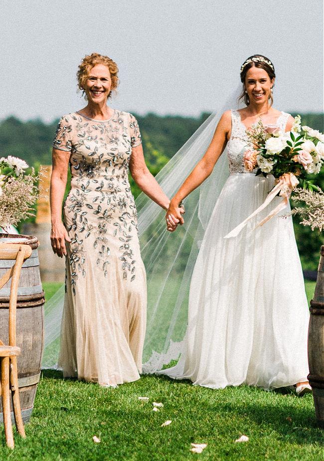 Ann-Banks wearing blush and sliver Mother of the bride dress walking with bride