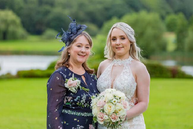 Jane-Williams in navy floral Mother of the bride dress and hat with bride